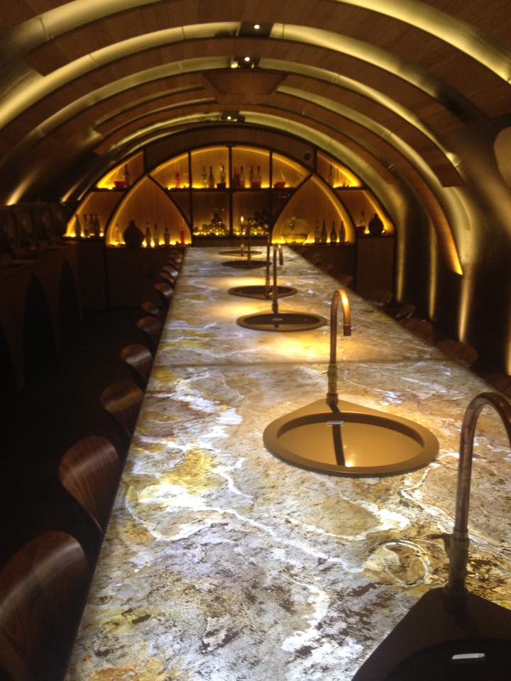 Bar Voûté Luxe : Dégustation Vin ou Cocktail Design Bar voûté luxueux avec plafond en bois, comptoir en pierre rétroéclairé et robinets individuels en cuivre le long de la table.